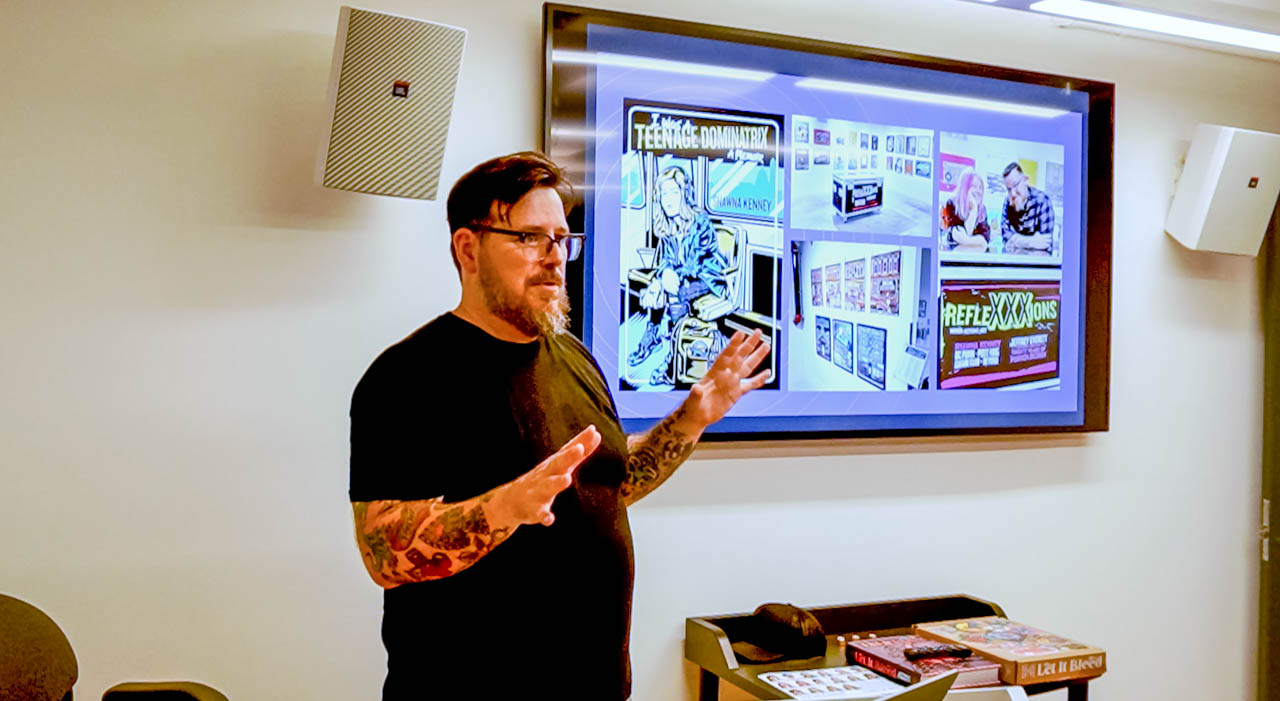 speaker talking in front of a monitor showing his work